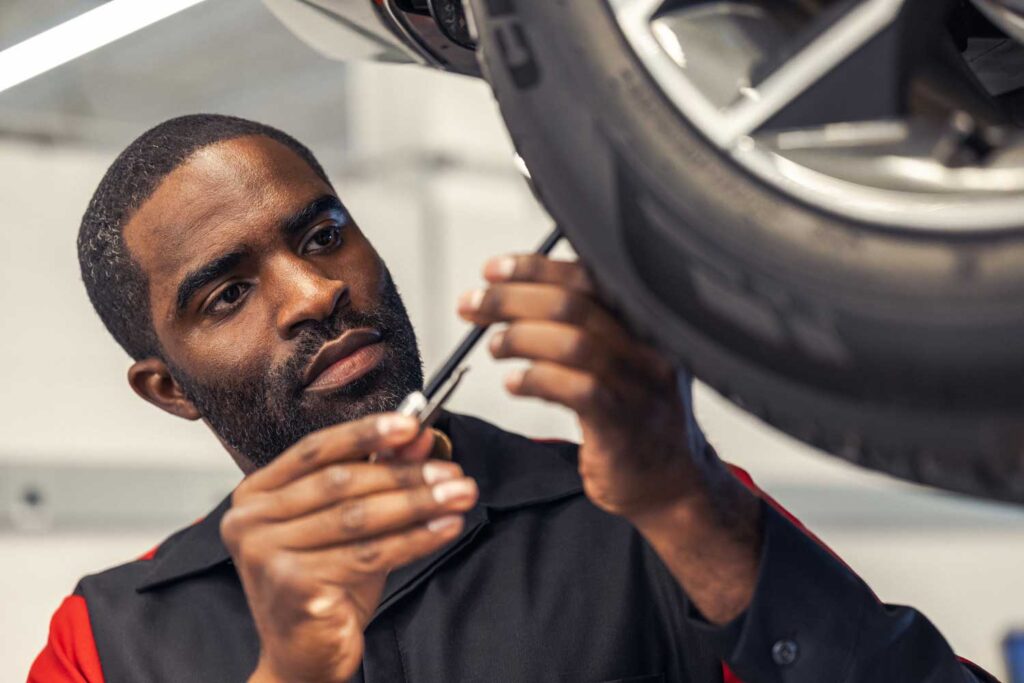 Technician inspecting a tire on a raised vehicle.