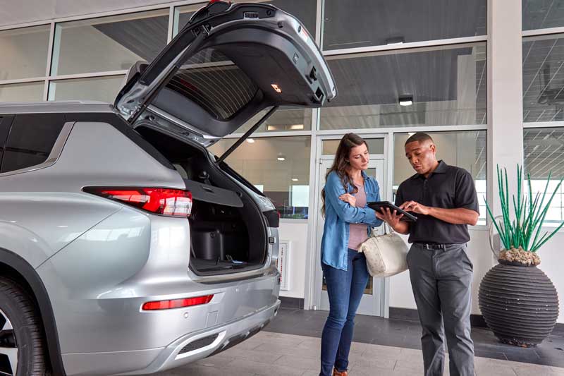 Customer and service advisor beside a vehicle in a dealership service area